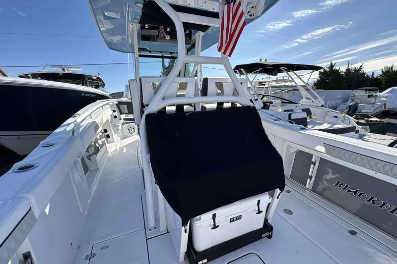 Slide: The Image of 2024 Blackfin 302CC boat interior with seating and cooler, docked under clear sky. - 16