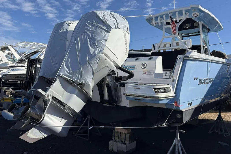Slide: The Image of 2024 Blackfin 302CC boat with twin outboard engines, docked and covered, under a clear blue sky. - 17