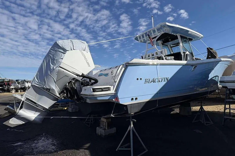 Slide: The Image of 2024 Blackfin 302CC boat with Mercury engine, displayed on stands under a clear blue sky. - 6