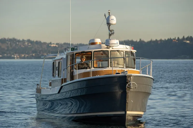 The Image of 2026 Ranger Tugs R-31S cruising on a calm lake with scenic background. - 1