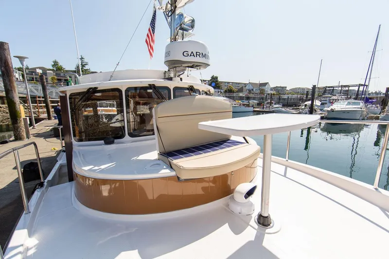 Slide: The Image of 2026 Ranger Tugs R-31S boat docked, featuring a seating area and table on deck. - 11