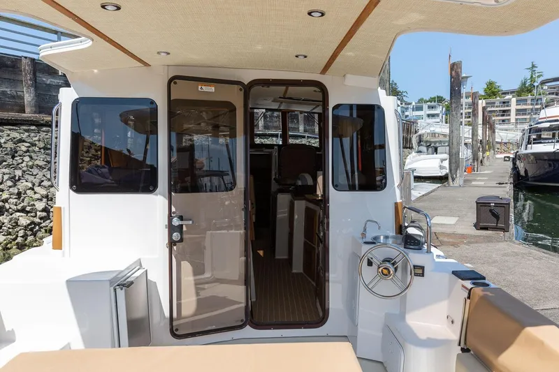 Slide: The Image of 2026 Ranger Tugs R-31S boat docked, showcasing rear deck and interior entrance. - 14