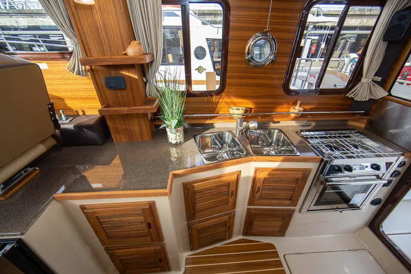Slide: The Image of 2026 Ranger Tugs R-31S interior kitchen with wood finish, dual sinks, and stove. - 26