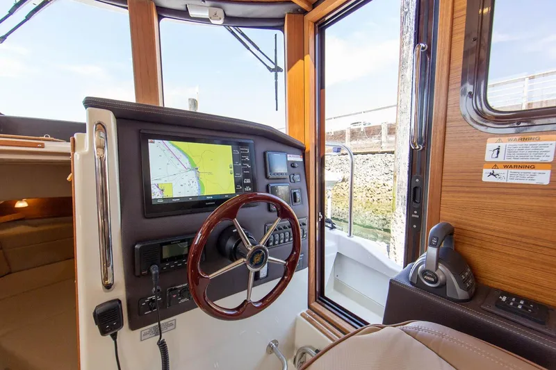 Slide: The Image of 2026 Ranger Tugs R-31S helm with navigation display and wooden steering wheel. - 33