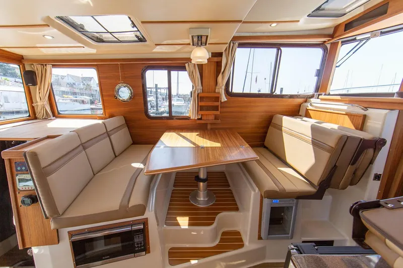 Slide: The Image of Interior of 2026 Ranger Tugs R-31S, featuring a cozy dining area with wood accents. - 34