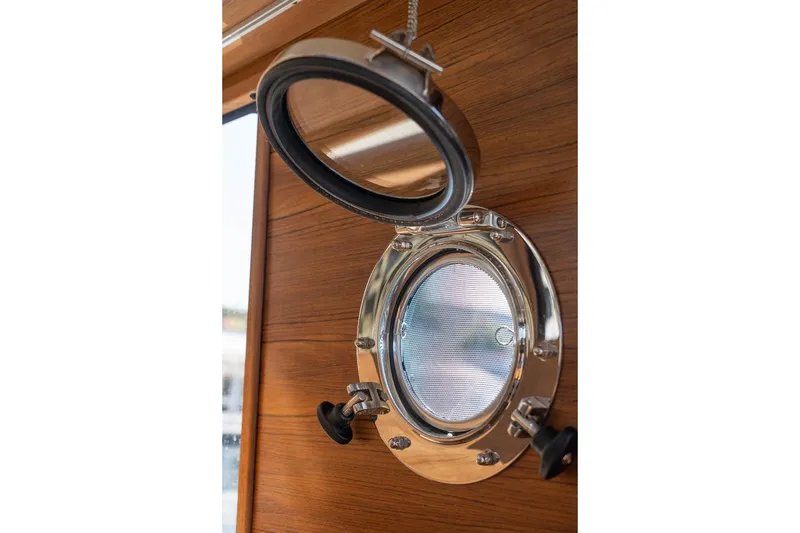 Slide: The Image of Porthole on 2026 Ranger Tugs R-31S, showcasing polished metal and wood interior. - 39
