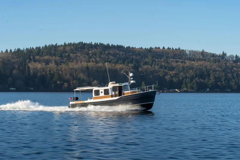 Slide: The Image of 2026 Ranger Tugs R-31S cruising on a serene lake with forested shoreline. - 4
