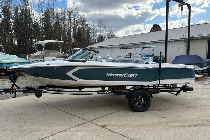 The Image of 2025 MasterCraft ProStar boat on trailer, parked outdoors near other boats. - 0