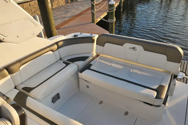 Slide: The Image of 2015 Monterey 315 Sport Yacht interior seating by the dock, featuring elegant white and gray upholstery. - 15