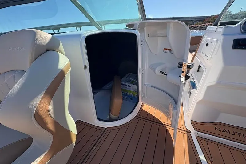 Slide: The Image of 2026 NauticStar 223 DC Deck boat interior with open storage compartment. - 16