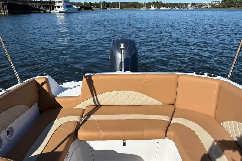 Slide: The Image of 2026 NauticStar 223 DC Deck boat interior with tan seating on calm water. - 6