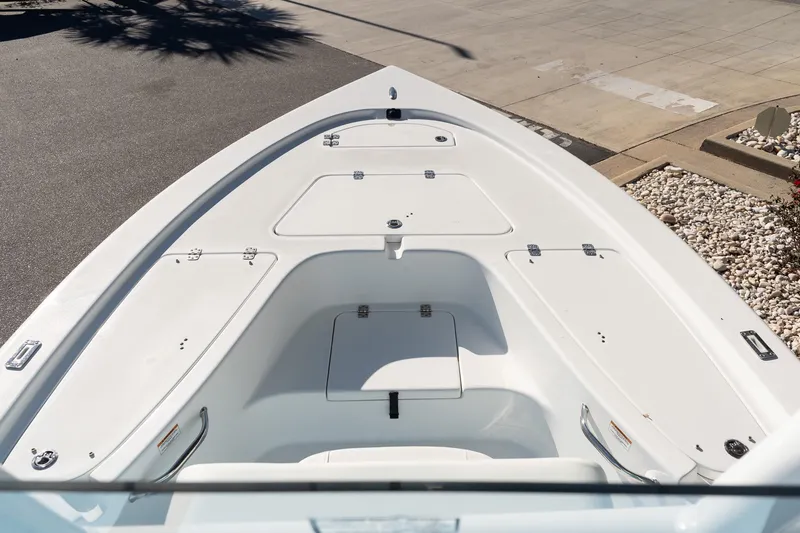 Slide: The Image of 2026 Sea Pro 230 Bay boat deck with storage compartments, parked on pavement. - 15