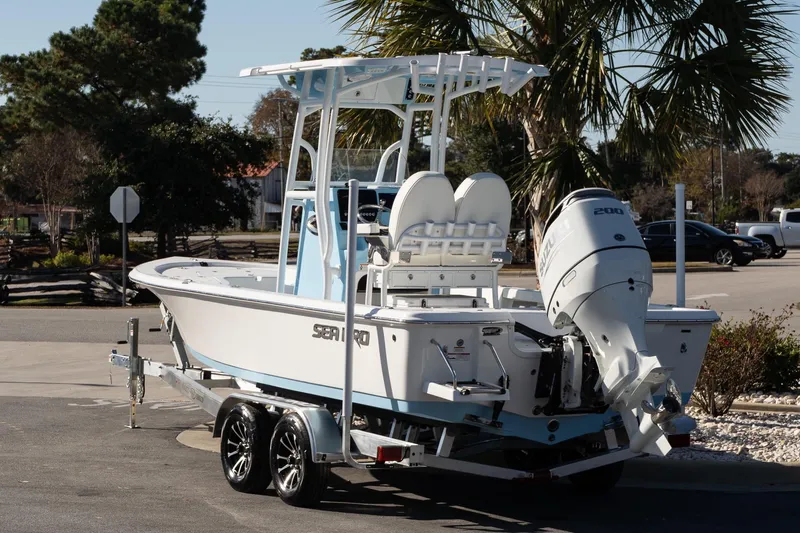 Slide: The Image of 2026 Sea Pro 230 Bay boat on trailer with outboard motor, parked outdoors. - 3