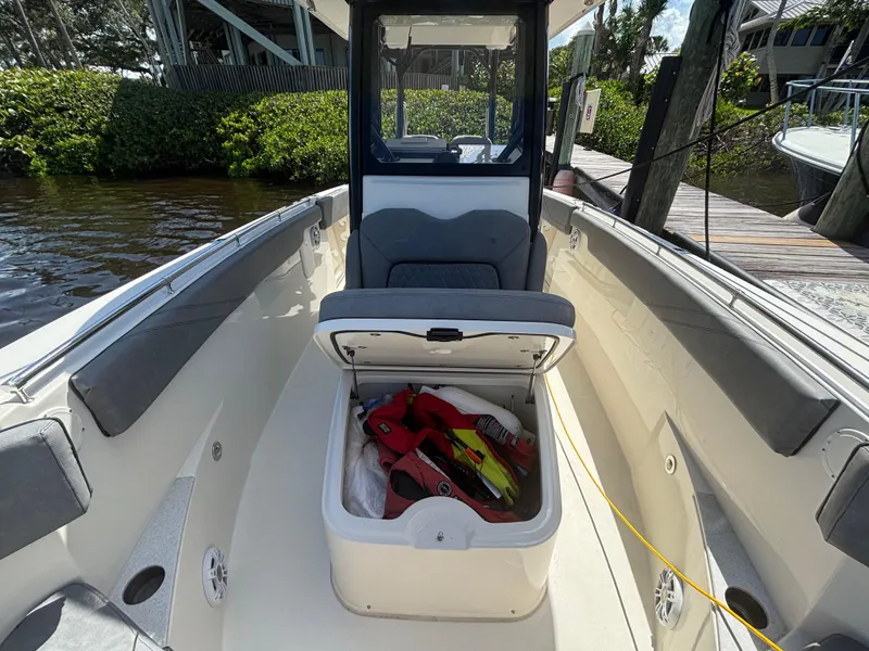Slide: The Image of 2023 Stingray 273 CC boat interior with open storage compartment, dockside view. - 11