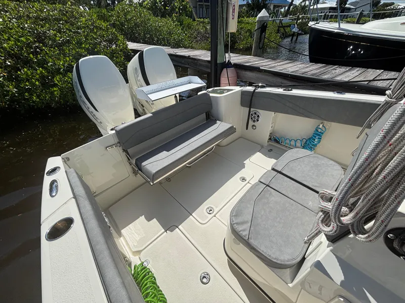 Slide: The Image of 2023 Stingray 273 CC boat interior with seating and dual engines at a dock. - 17