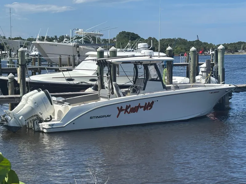 Slide: The Image of 2023 Stingray 273 CC boat docked at marina, featuring dual outboard engines. - 2
