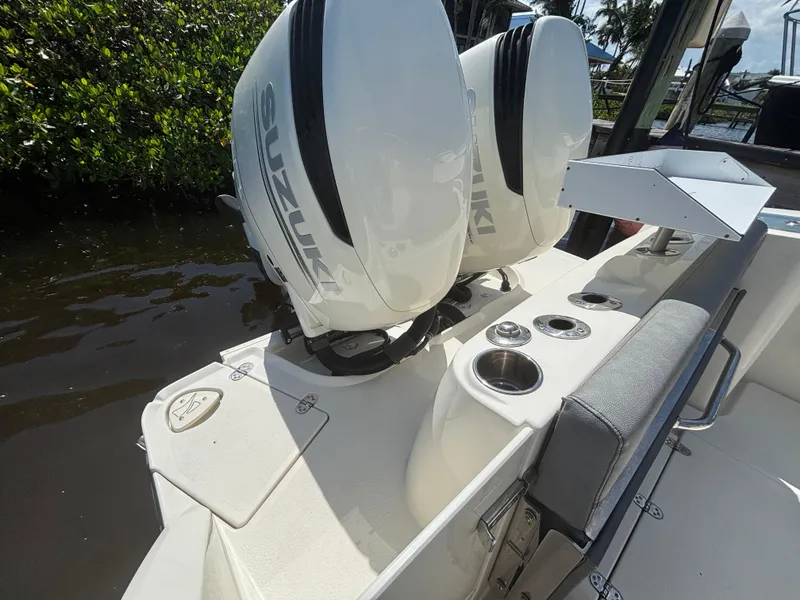 Slide: The Image of 2023 Stingray 273 CC boat with dual Suzuki outboard motors, docked near lush greenery. - 21