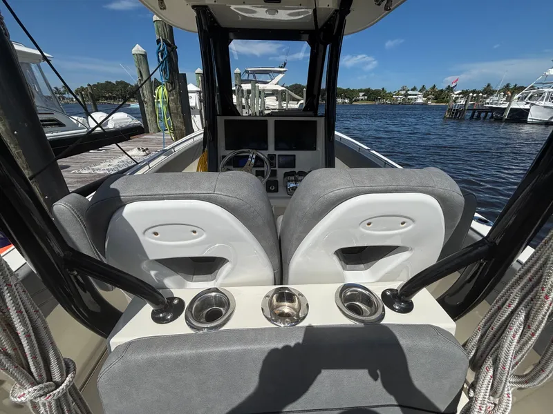 Slide: The Image of 2023 Stingray 273 CC boat interior with dual seats and cup holders at a marina. - 24