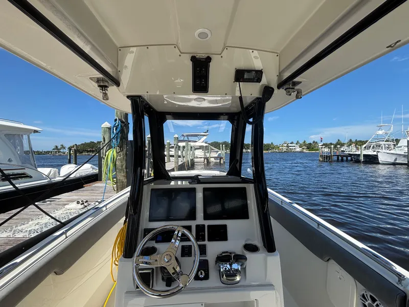 Slide: The Image of 2023 Stingray 273 CC boat interior with steering wheel and control panel at marina. - 26