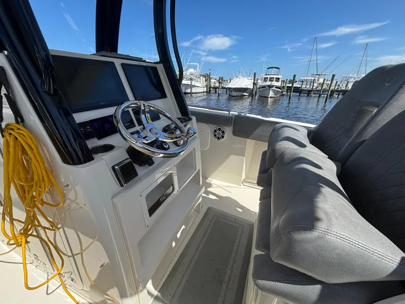 Slide: The Image of 2023 Stingray 273 CC boat interior with steering wheel and dual screens at marina. - 29