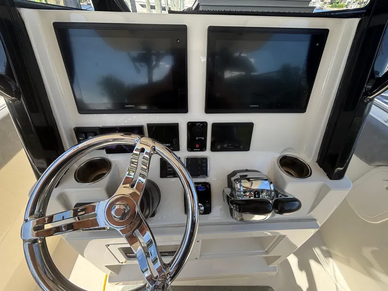 Slide: The Image of 2023 Stingray 273 CC boat dashboard with dual Garmin screens and chrome steering wheel. - 30