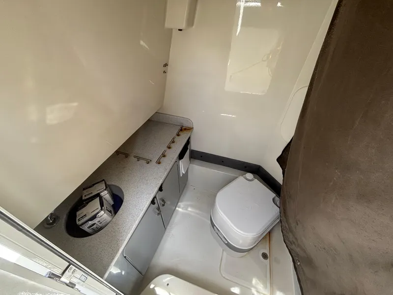 Slide: The Image of 2023 Stingray 273 CC boat interior with compact bathroom and storage area. - 32