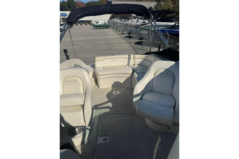 Slide: The Image of 2008 Sea Ray 260 Sundeck interior with beige seating and canopy, docked outdoors. - 14
