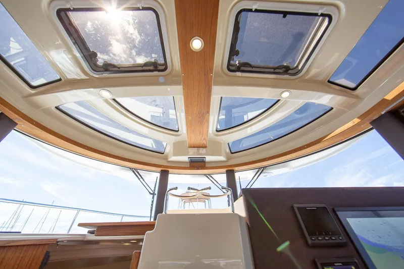 Slide: The Image of Interior view of 2026 Ranger Tugs R-29CB with sunlit skylights and modern dashboard. - 12