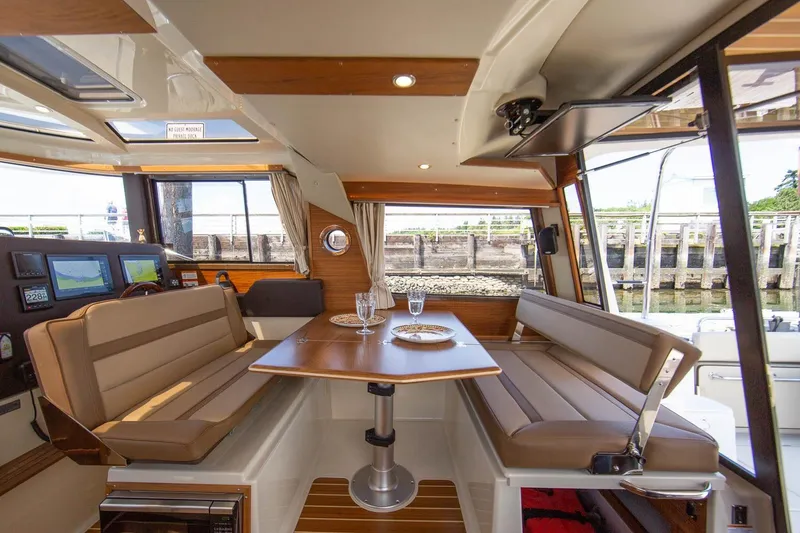 Slide: The Image of 2026 Ranger Tugs R-29CB interior with dining area, elegant seating, and scenic window views. - 14