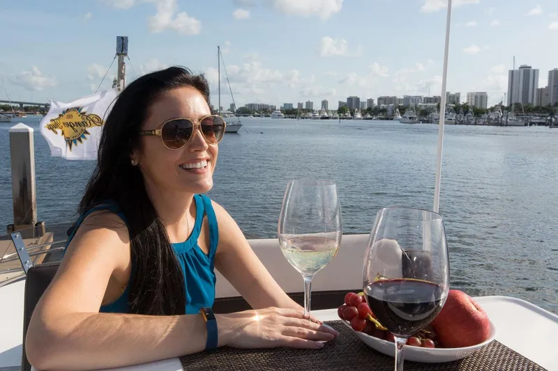 Slide: The Image of Woman enjoying wine and fruit on a 2026 Ranger Tugs R-29CB boat, with waterfront view. - 22
