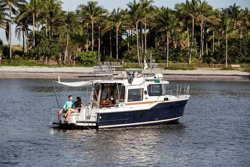 Slide: The Image of 2026 Ranger Tugs R-29CB cruising near a tropical shoreline with palm trees. - 26