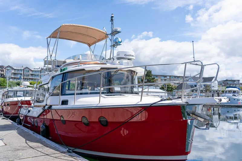 Slide: The Image of 2026 Ranger Tugs R-29CB boat docked at marina, featuring red hull and upper deck canopy. - 38