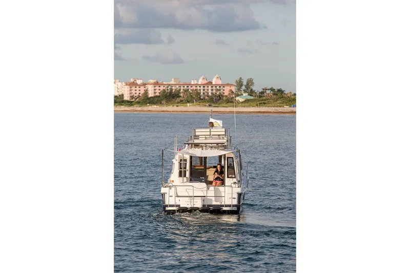 Slide: The Image of 2026 Ranger Tugs R-29CB cruising on water near coastal buildings. - 41