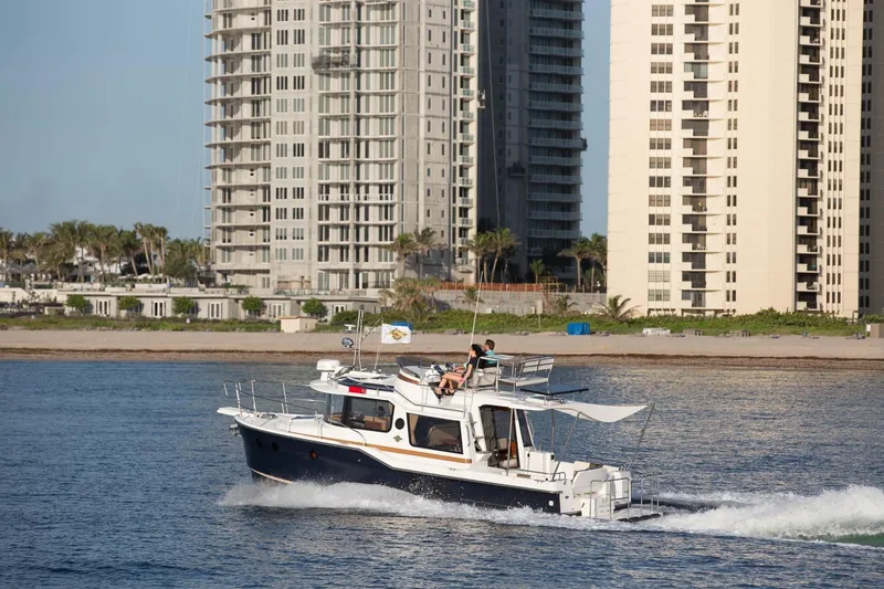 Slide: The Image of 2026 Ranger Tugs R-29CB cruising near tall beachfront buildings. - 43