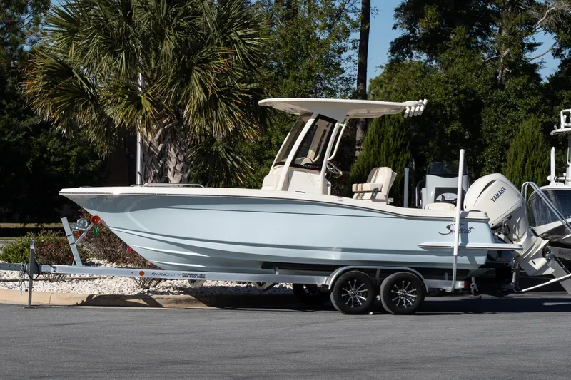 The Image of 2026 Scout 220 XSF boat on trailer, parked outdoors near palm trees. - 1