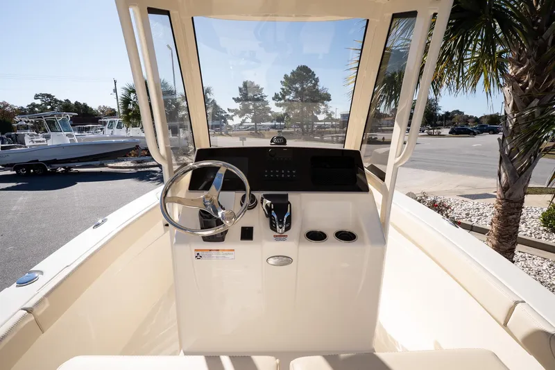 Slide: The Image of 2026 Scout 220 XSF boat cockpit with steering wheel and controls, parked near palm trees. - 12