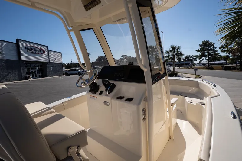 Slide: The Image of 2026 Scout 220 XSF boat interior at dealership, showcasing helm and seating area. - 13