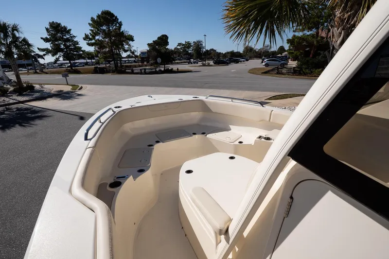 Slide: The Image of 2026 Scout 220 XSF boat interior with seating, parked near a road with trees. - 14