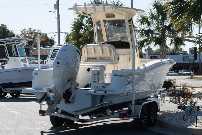 Slide: The Image of 2026 Scout 220 XSF boat on trailer, parked outdoors with palm trees in background. - 6