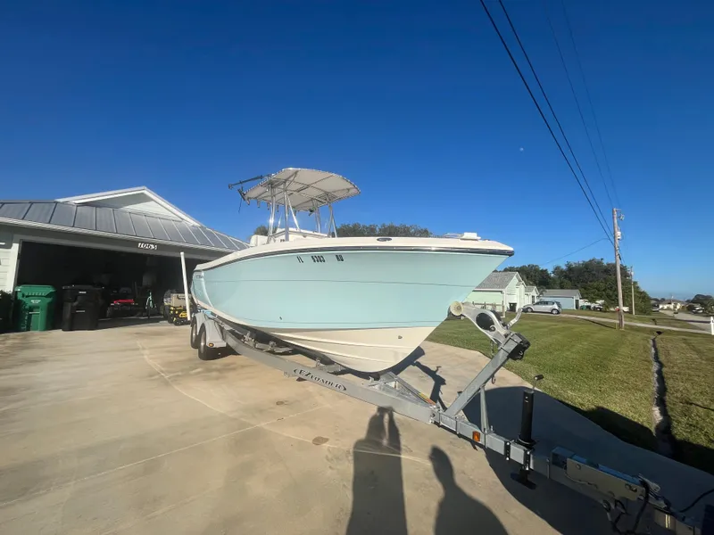 Slide: The Image of 2019 Cobia 237 Center Console boat on trailer in driveway under clear blue sky. - 12