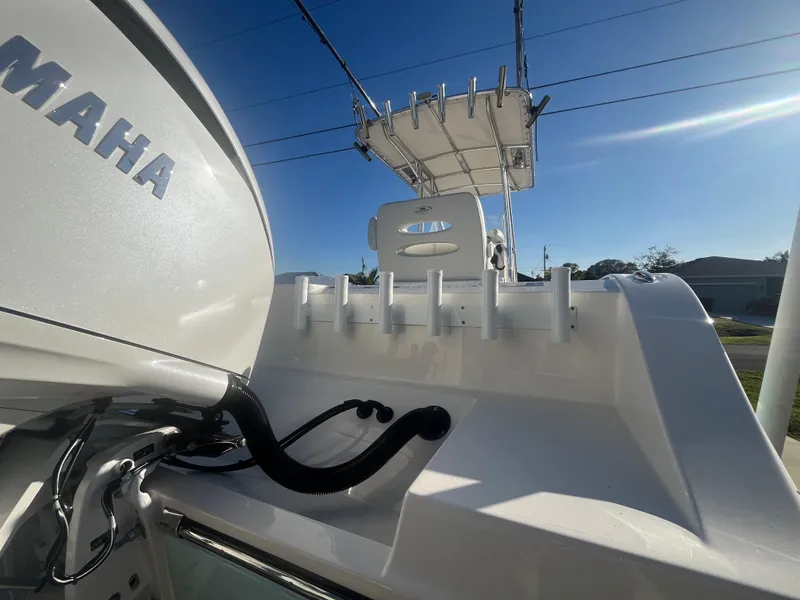Slide: The Image of 2019 Cobia 237 Center Console boat with Yamaha engine, rod holders, and T-top under clear sky. - 19