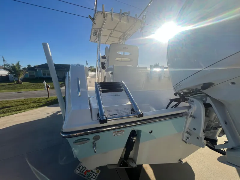 Slide: The Image of 2019 Cobia 237 Center Console boat with ladder and outboard motor in sunny driveway. - 20