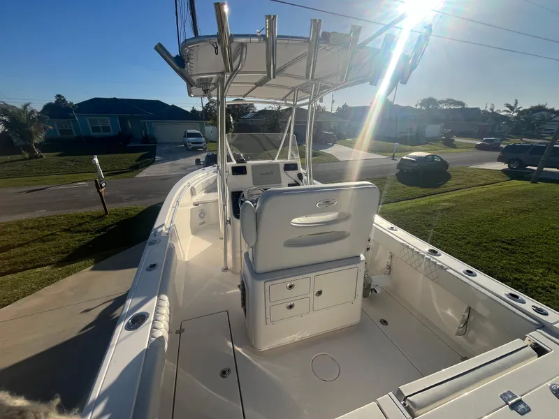 Slide: The Image of 2019 Cobia 237 Center Console boat with T-top, parked in a sunny residential area. - 22