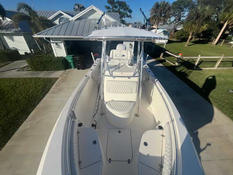 Slide: The Image of 2019 Cobia 237 Center Console boat parked in driveway, surrounded by greenery and houses. - 33