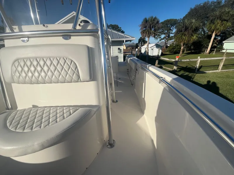 Slide: The Image of 2019 Cobia 237 Center Console boat interior with cushioned seating and sunny outdoor view. - 36