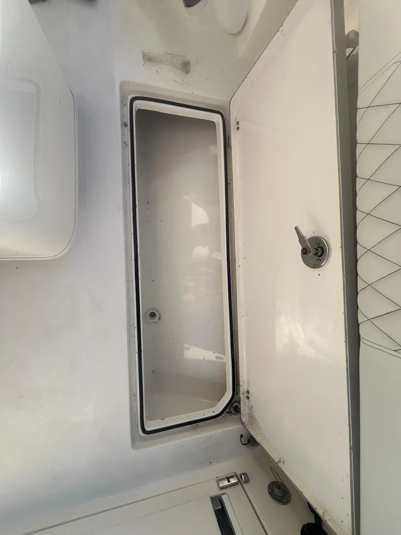 Slide: The Image of 2019 Cobia 237 Center Console boat storage compartment, open lid, white interior. - 45