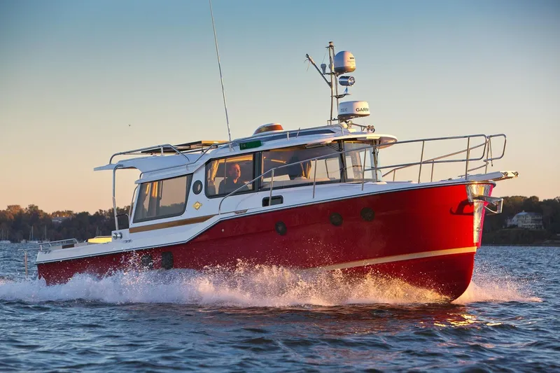 The Image of 2026 Ranger Tugs R-29S cruising on water at sunset, showcasing sleek red design. - 1