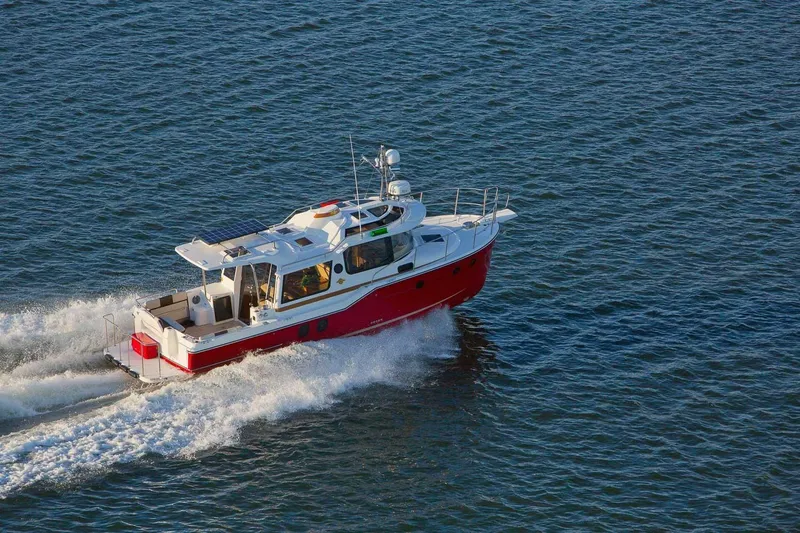 Slide: The Image of 2026 Ranger Tugs R-29S cruising on open water, showcasing sleek design and vibrant red hull. - 7