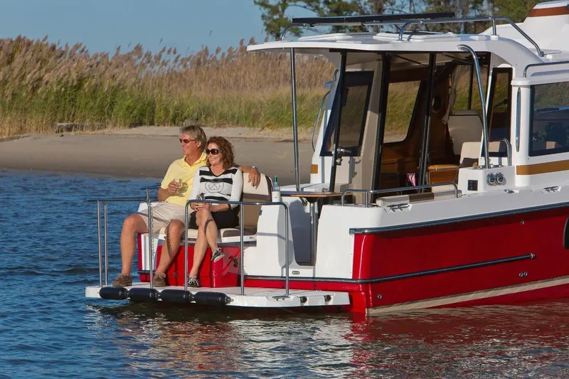 Slide: The Image of Couple relaxing on 2026 Ranger Tugs R-29S boat near a sandy shore. - 8