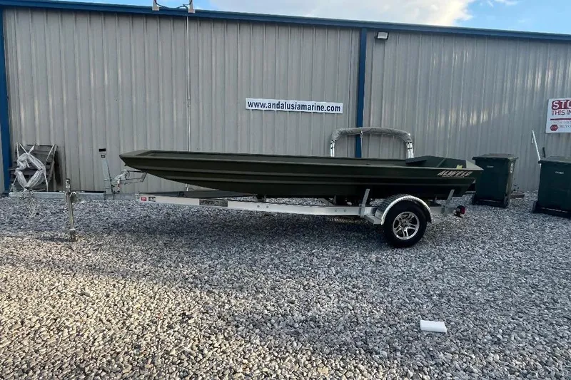 Slide: The Image of 2026 Alweld 1648 Marsh Jon boat on trailer, parked outside a marine shop. - 4